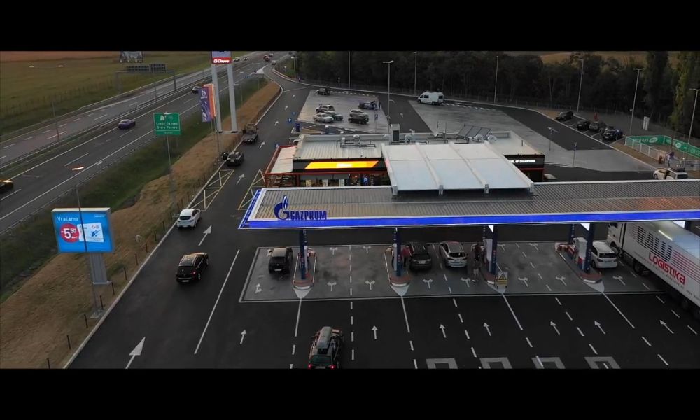 Benzinska pumpa pored autoputa sa automobilima i kamionima.